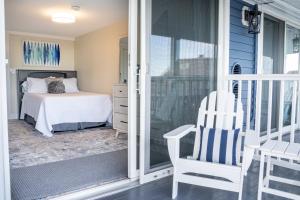 Cette chambre comprend un lit et une chaise sur une terrasse couverte. dans l'établissement 935 Ocean, a Beachside Inn, à Hampton Beach