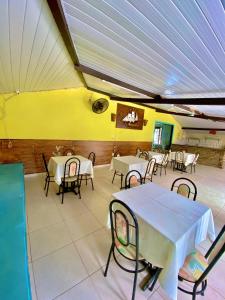un restaurant avec des tables et des chaises et un mur jaune dans l'établissement Pousada Elpirata Sidney, à Ceará-Mirim