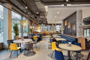 a restaurant with yellow and blue chairs and tables at H2 Hotel Mainz in Mainz