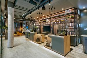 a lobby with tables and a tv and books at H2 Hotel Mainz in Mainz
