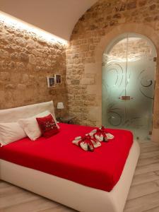 sypialnia z dużym czerwonym łóżkiem z butami w obiekcie Casa vacanze Modica Charme w mieście Modica