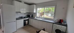 a kitchen with white cabinets and a dog looking out the window at Villa Verde Pet-friendly in Córdoba