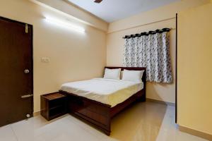 OYO Hotel SD في بانغالور: غرفة نوم صغيرة بها سرير ونافذة
