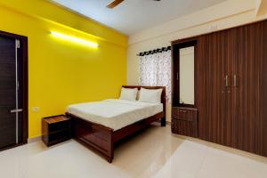 OYO Hotel SD في بانغالور: غرفة نوم بسرير وجدار اصفر