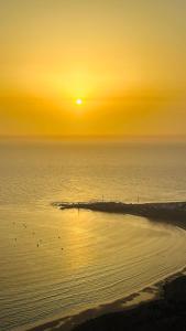 einen Sonnenuntergang über einem Strand mit Vögeln im Wasser in der Unterkunft Surf Break Morocco in Imsouane