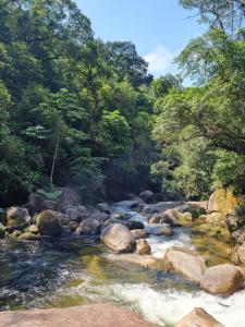 a river with rocks and trees in the background at LARA'S HOUSE in São Sebastião