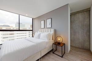 a bedroom with a large white bed and a window at Inigualable Loft en el norte. in Bogotá