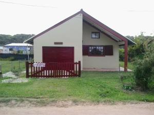 una pequeña casa blanca con una puerta roja en ANAHATA, en Barra del Chuy