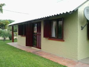 a green house with red shutters on it at ANAHATA in Barra del Chuy