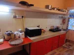 a kitchen with red cabinets and a microwave on a counter at Himshikha Homestay in Darjeeling