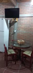uma mesa de vidro com 2 cadeiras e um frigorífico em El Refugio em San Fernando del Valle de Catamarca