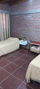 a room with two beds and a brick wall at El Refugio in San Fernando del Valle de Catamarca