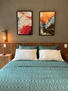 a bedroom with a bed with three paintings on the wall at Palulu Flat - Conforto e Conveniência Garantidos - Ar Condicionado - Área de Lazer com Piscina e Sauna - Garagem Subterrânea - Serviço de Praia in Juquei