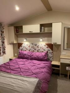 een slaapkamer met een paars bed en een spiegel bij Foxglove Fourteen in Saint Leonards