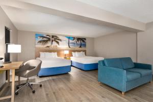 a hotel room with two beds and a desk and a chair at Days Inn by Wyndham Miami Airport North in Miami