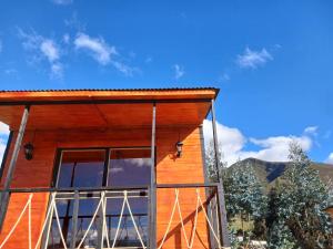 ein Holzhaus mit einem großen Fenster in der Unterkunft Hospedaje cabaña Guatavita Finca las Acacias in Guatavita