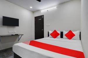 a bedroom with a bed with red pillows and a television at OYO Flagship IKON Stay and Restaurant in Hyderabad