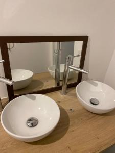 a bathroom with two white sinks and a mirror at La suite du Docteur Privey in Tournus