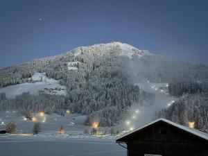 a snow covered mountain with a ski lodge in front of it at Appartements Michaela in Westendorf