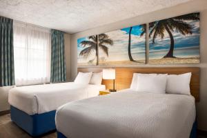 two beds in a hotel room with palm trees at Days Inn by Wyndham Miami Airport North in Miami