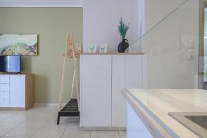 a kitchen with white cabinets and a painting on the wall at Seaside Apartment in Salamís