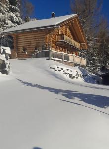 ein Blockhaus im Schnee mit Fußabdrücken in der Unterkunft Almhaus Heidi Nockberge in Patergassen