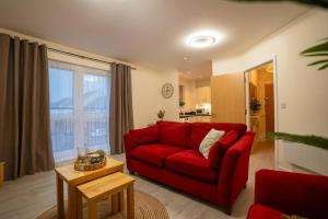 a living room with a red couch and a table at Cosy 2 Bedroom flat in Stevenage in Stevenage