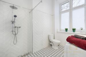 uma casa de banho branca com um chuveiro e um WC. em Royal Style Apartment em Lódź