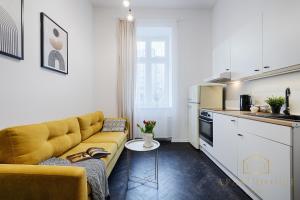 a living room with a yellow couch and a kitchen at Royal Style Apartment in Łódź