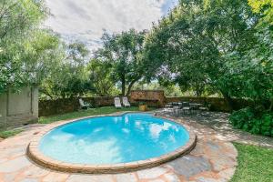 een zwembad in een tuin met een tafel en stoelen bij La Bastide Guest House in Hartbeespoort