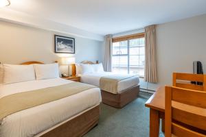 a hotel room with two beds and a window at Sundance Lodge in Sun Peaks