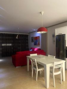 een woonkamer met een witte tafel en een rode bank bij Emma & Ella Apartment in Tirana