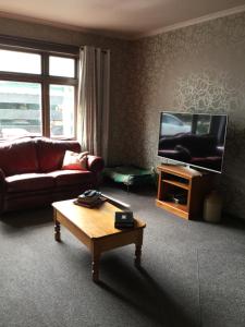 a living room with a couch and a flat screen tv at Stay@10 in Blenheim