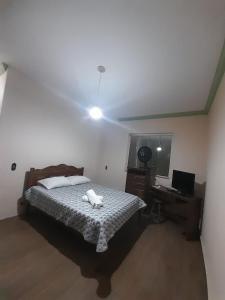 a bedroom with a bed and a desk with a laptop at Pouso da Praça in Bonfim