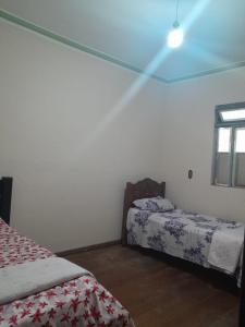 a bedroom with two beds and a window at Pouso da Praça in Bonfim