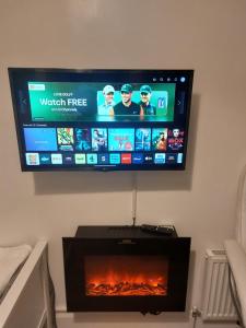 a flat screen tv hanging on a wall with a fireplace at De lick strawberry studio in London