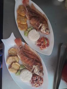Mi Cabañita Guest House في بلايا بلانكا: طبقين من الطعام مع الأسماك على طاولة