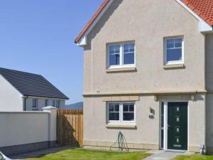 una casa con una puerta verde y una valla en Faillie en Inverness