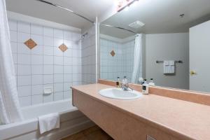 a bathroom with a sink and a tub and a mirror at Sundance Lodge in Sun Peaks