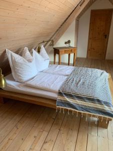 a bedroom with a bed with pillows and a wooden floor at Scheune im Grünen in Staufen im Breisgau