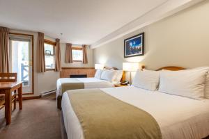 a hotel room with two beds and a desk at Sundance Lodge in Sun Peaks