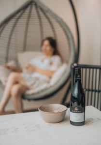 Una botella de vino sobre una mesa junto a una mujer. en Glenbosch Wine Estate Farm Stays, en Beechworth