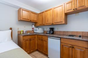 a small kitchen with wooden cabinets and a bed at Sundance Lodge in Sun Peaks