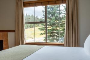 1 dormitorio con cama y ventana grande en Sundance Lodge en Sun Peaks