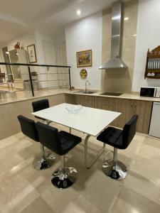 uma cozinha com uma mesa branca e cadeiras pretas em APARTAMENTO SAN JOSE em Palma del Río