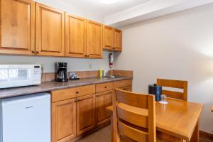a kitchen with wooden cabinets and a table with a microwave at Sundance Lodge in Sun Peaks
