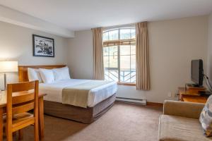 a hotel room with a bed and a desk and a window at Sundance Lodge in Sun Peaks
