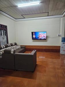 Muang PakxongにあるKai Lions International Hostelのリビングルーム(ソファ、薄型テレビ付)