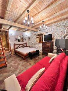 a living room with a large red couch and a bed at Magical cottage! in Agios Georgios Nilias