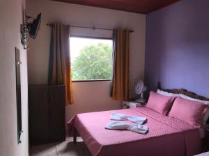 a bedroom with a pink bed with a window at Aconchego do céu in Conceição da Ibitipoca